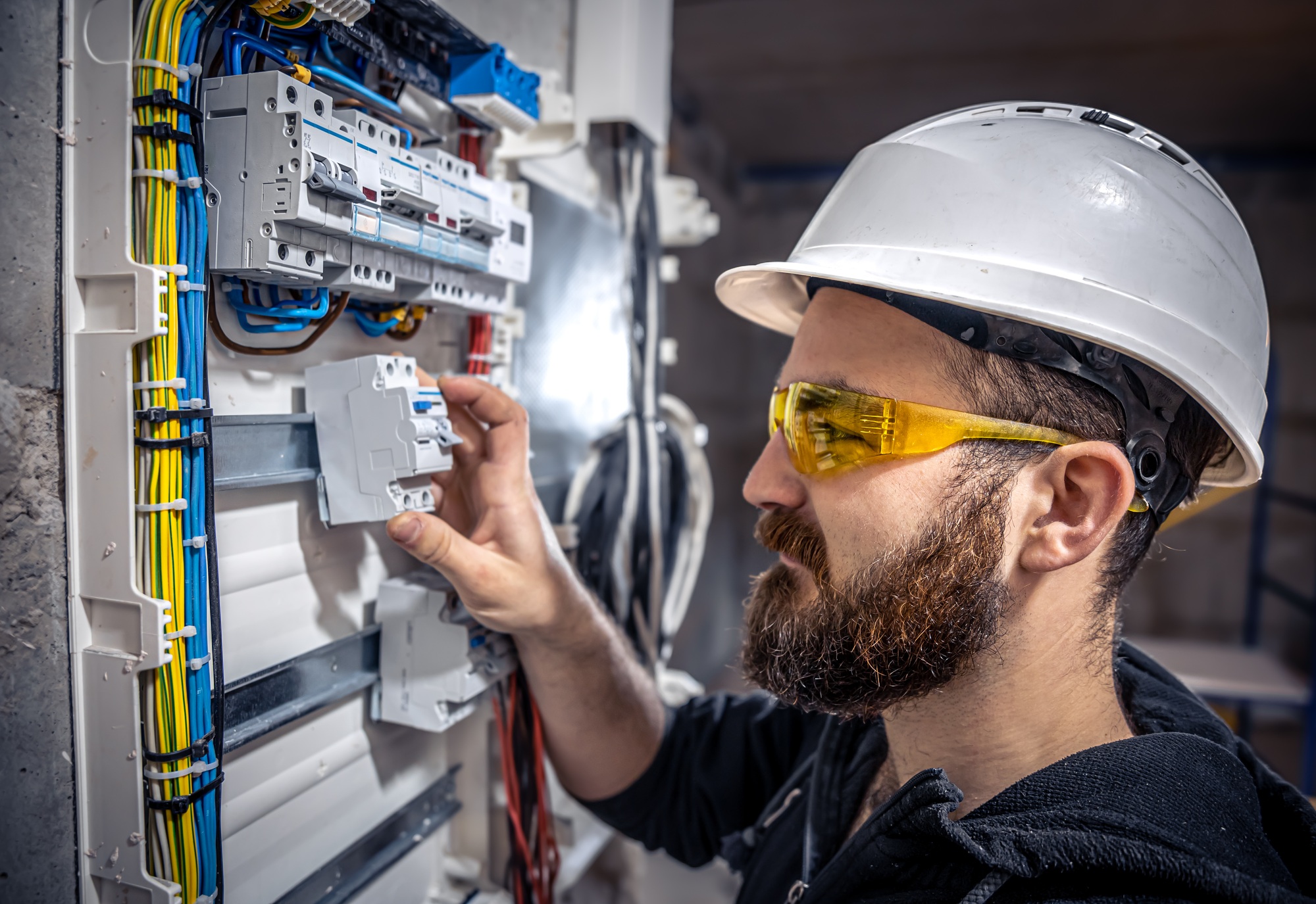 A male electrician works in a switchboard with an electrical connecting cable - INSTALACIONES ELECTRICAS A male electrician works in a switchboard with an electrical connecting cable.